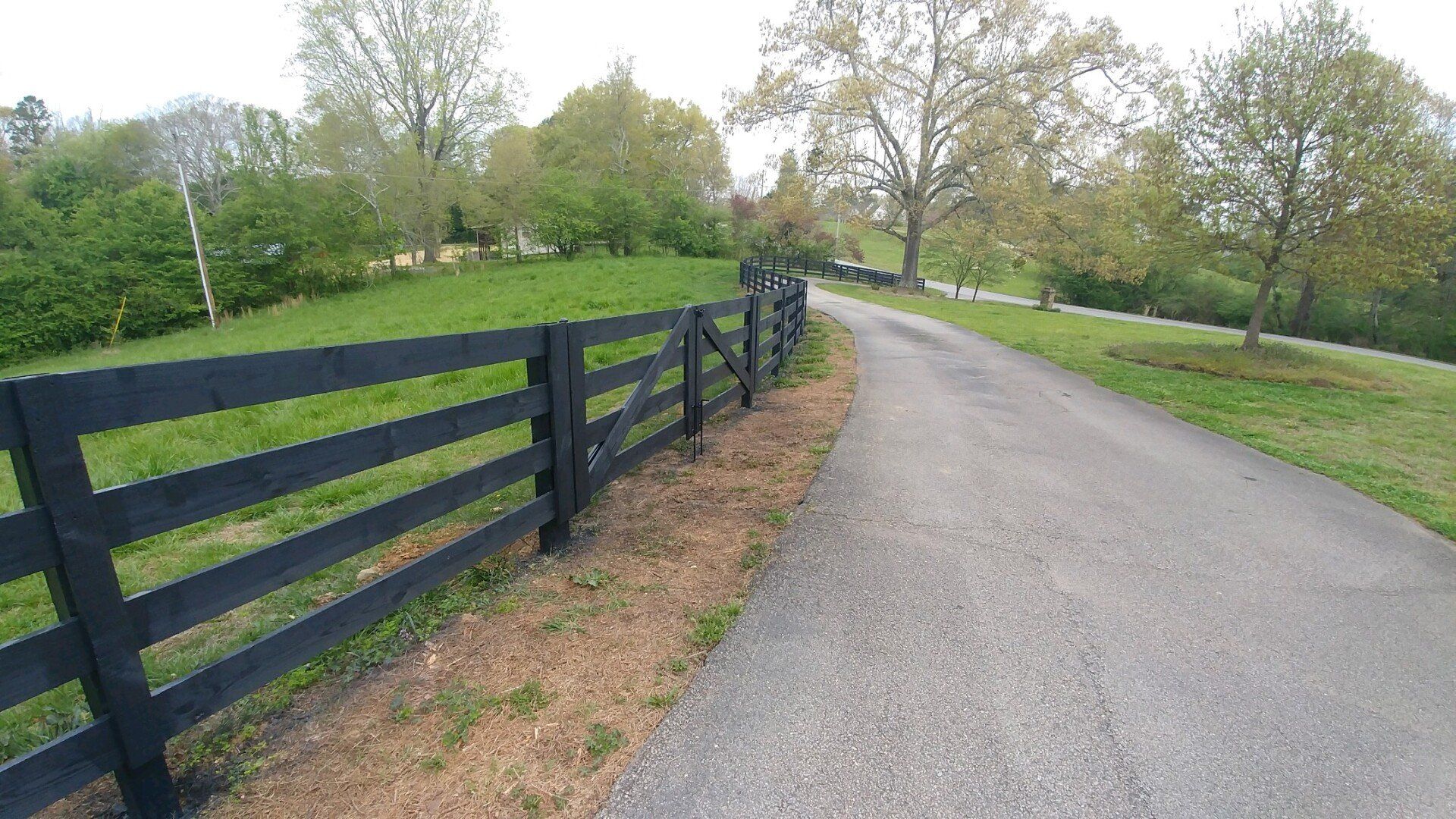 A black wooden fence along the side of a road.