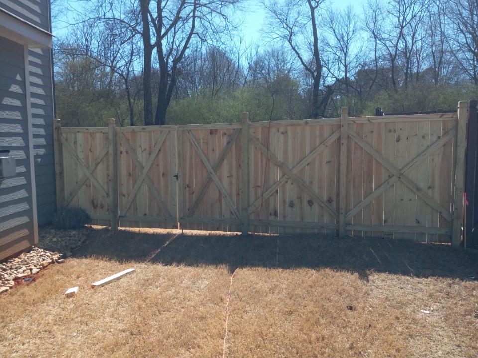 A wooden fence is in the backyard of a house