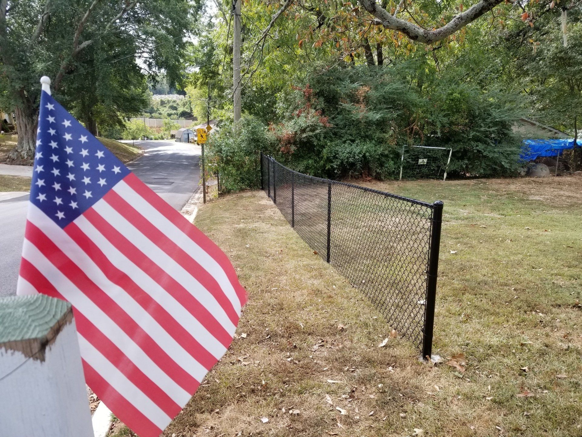 An american flag is flying in front of a chain link fence