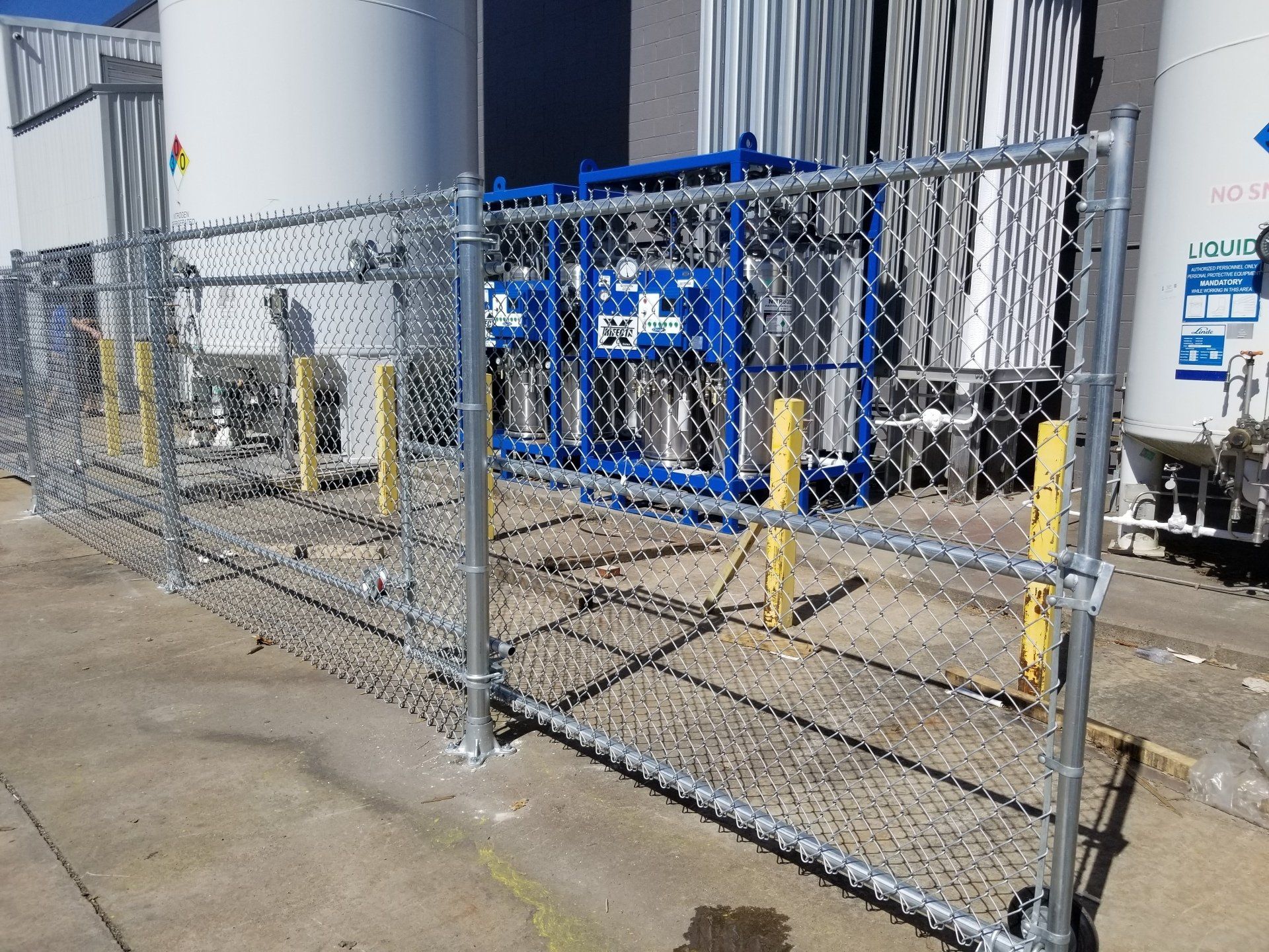 A chain link fence is surrounding a building with a lot of tanks in the background.