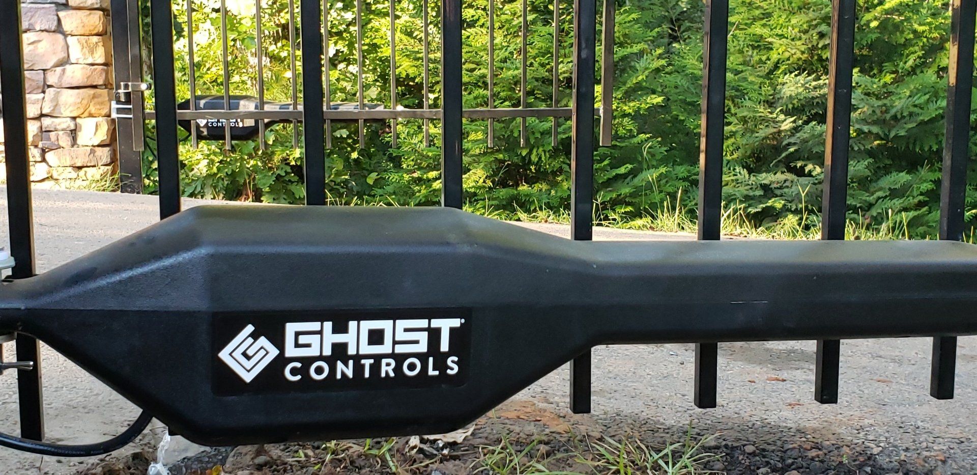 A black ghost controls gate motor is sitting next to a gate.