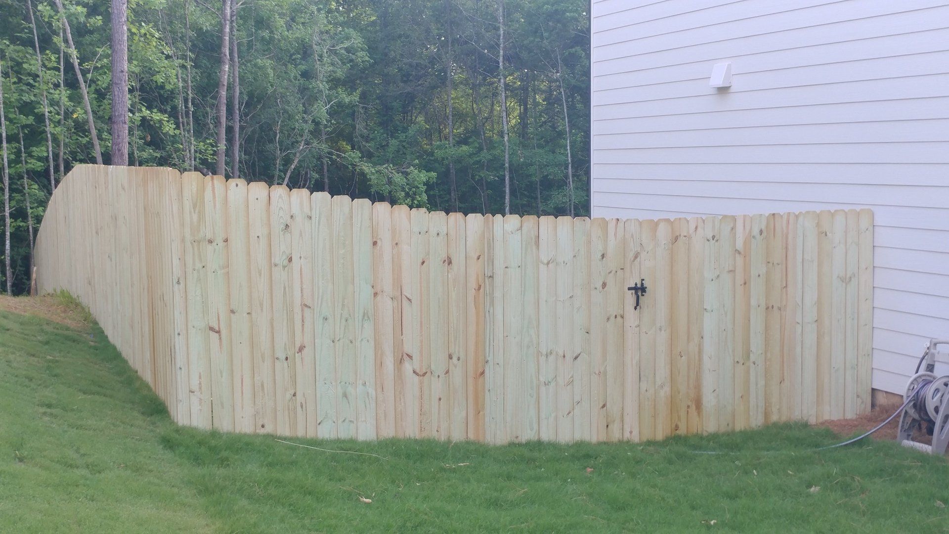 A wooden fence is in the backyard of a house.
