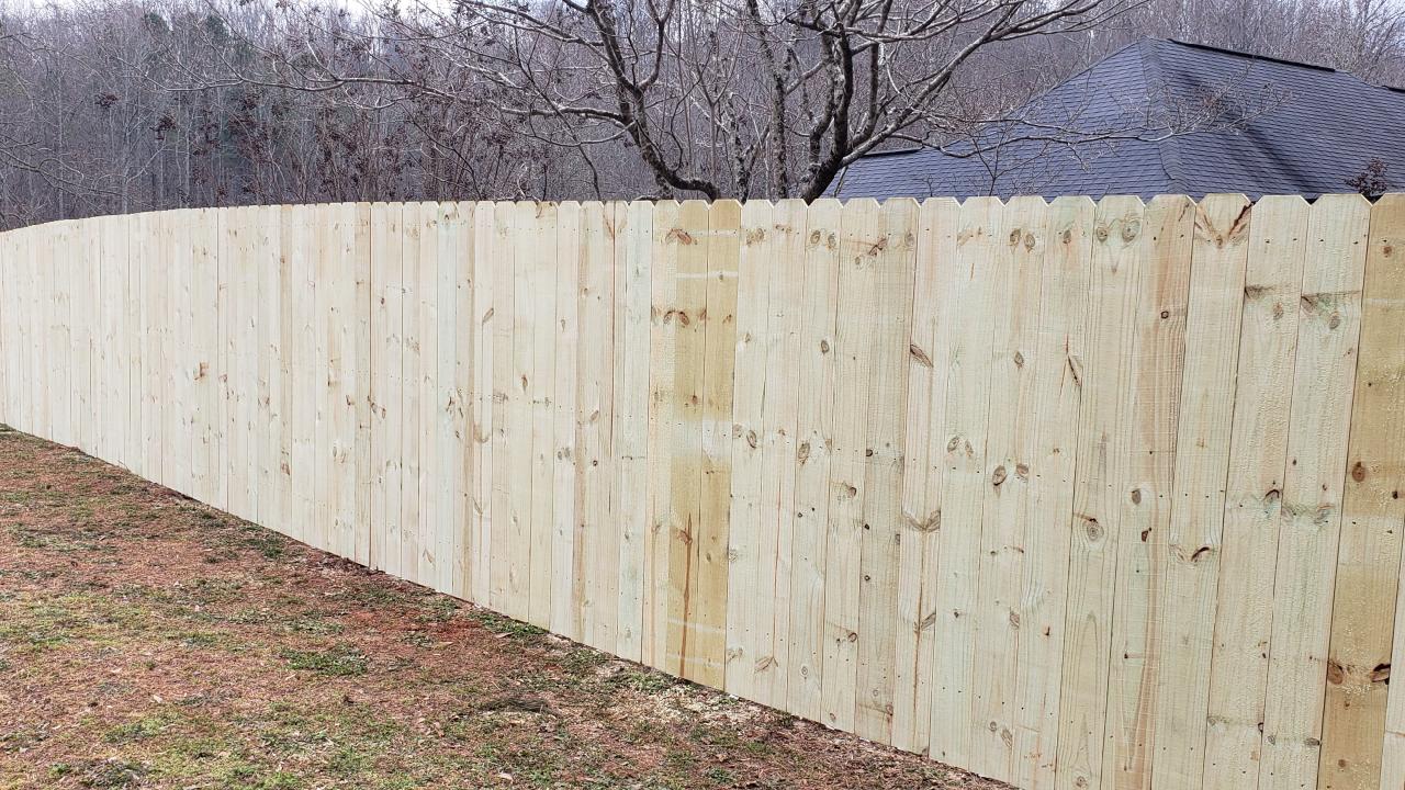 A long wooden fence is sitting in the middle of a grassy field.