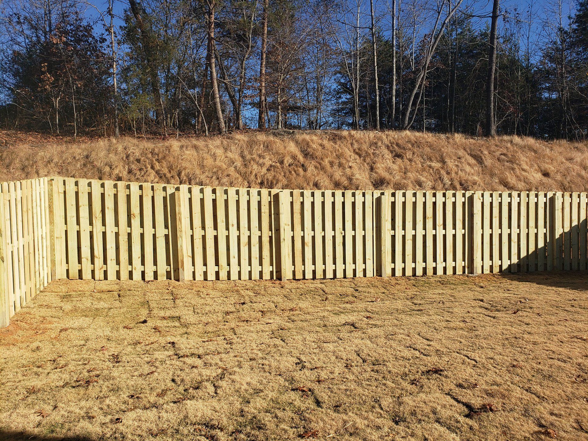 A wooden fence is sitting on top of a dry grass field.