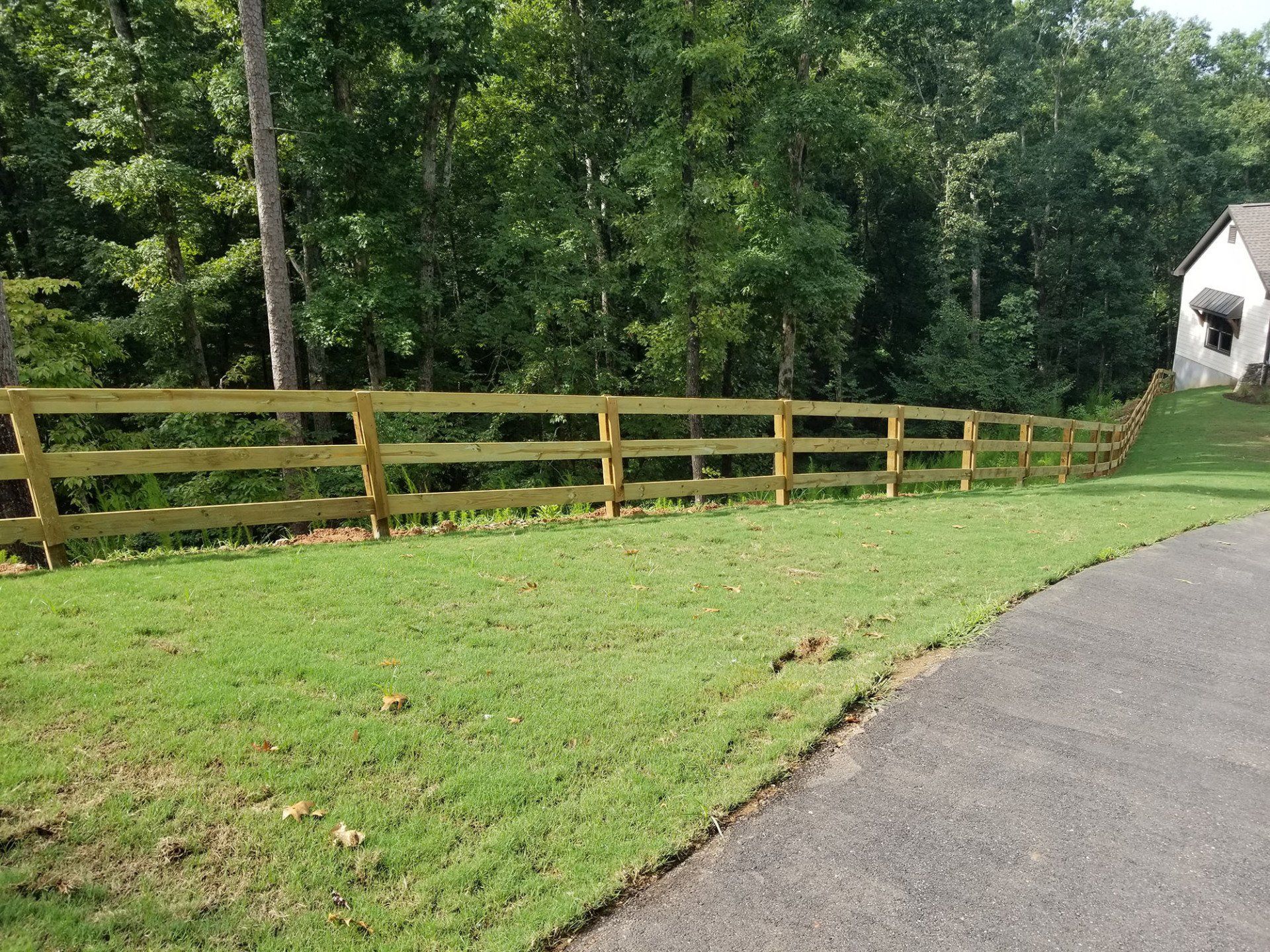 A wooden fence surrounds a lush green field.
