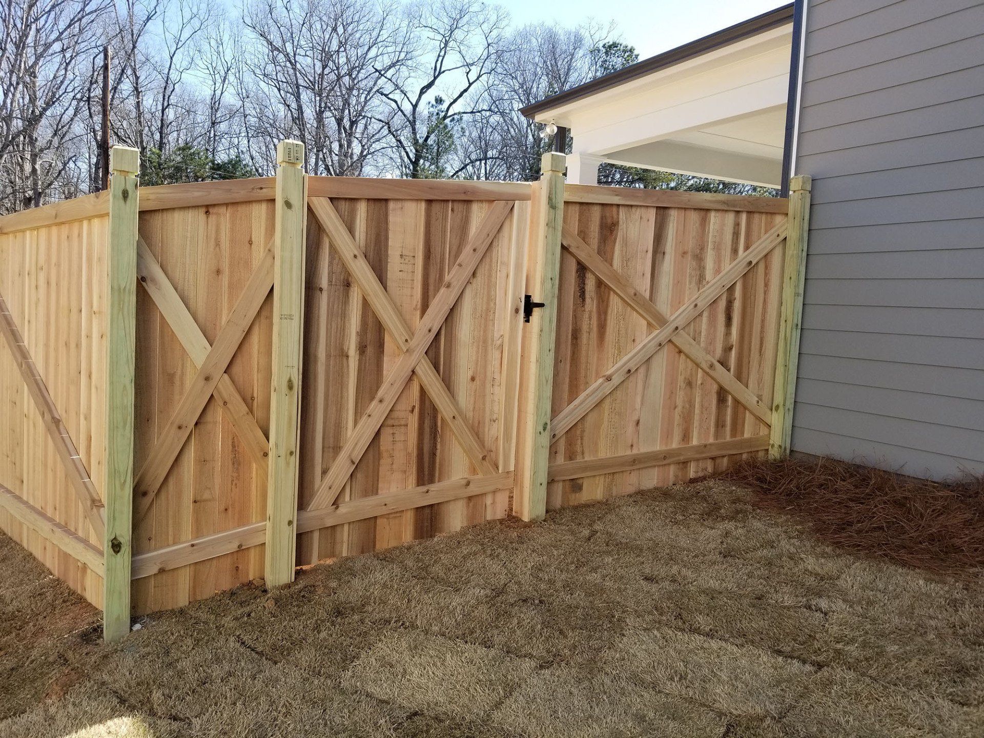 A wooden fence with a gate in front of a house.