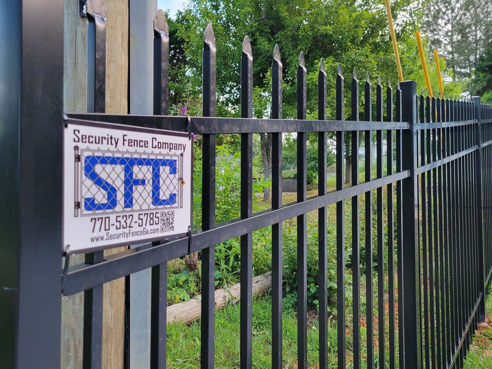 A black metal fence with a sign on it that says security fence company.
