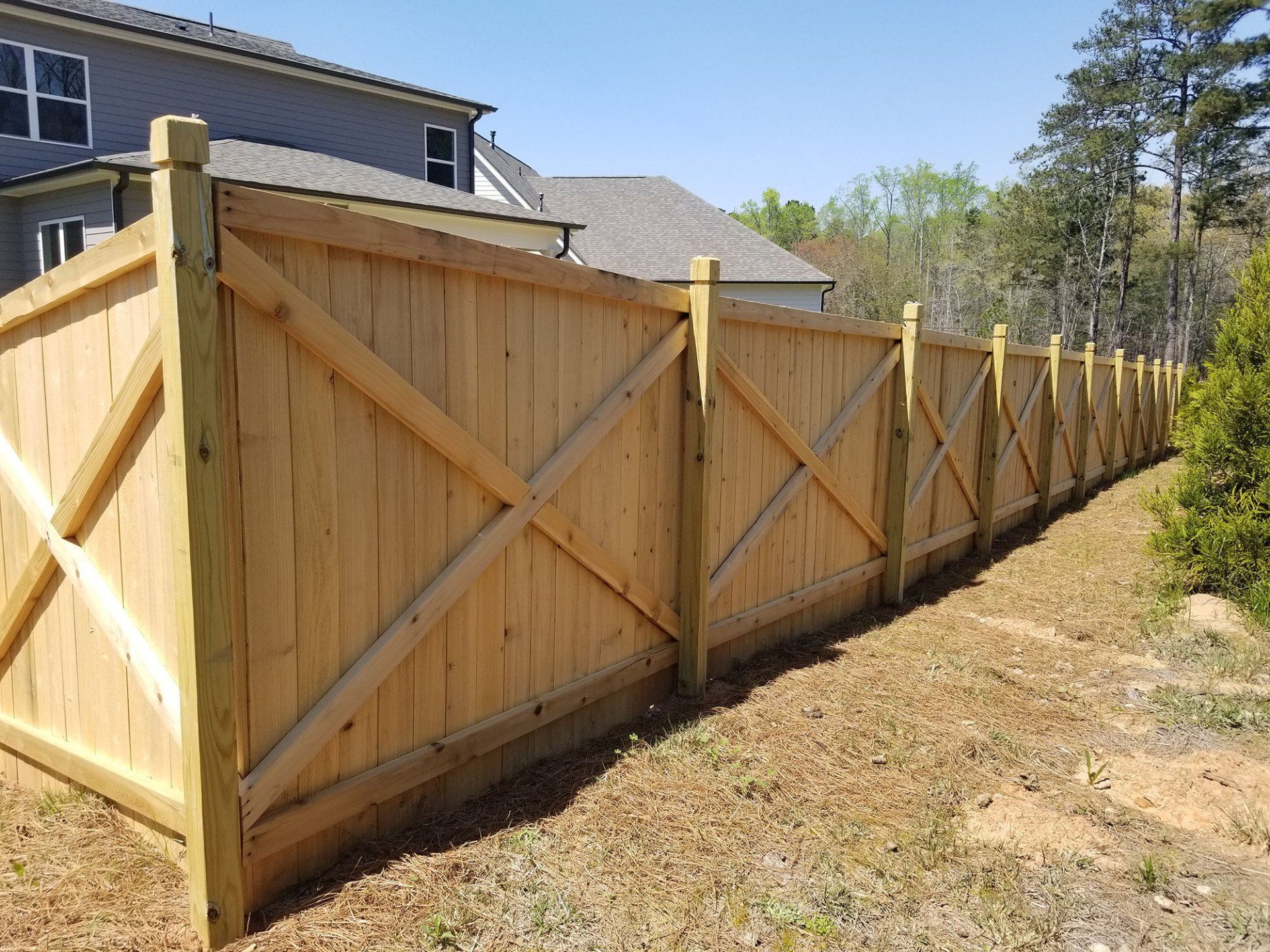 A wooden fence is sitting in the grass in front of a house.