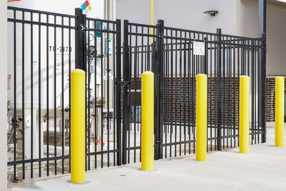 A black fence with yellow poles in front of it