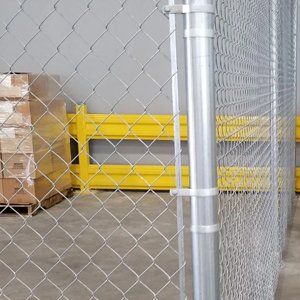 A chain link fence in a warehouse with boxes behind it.