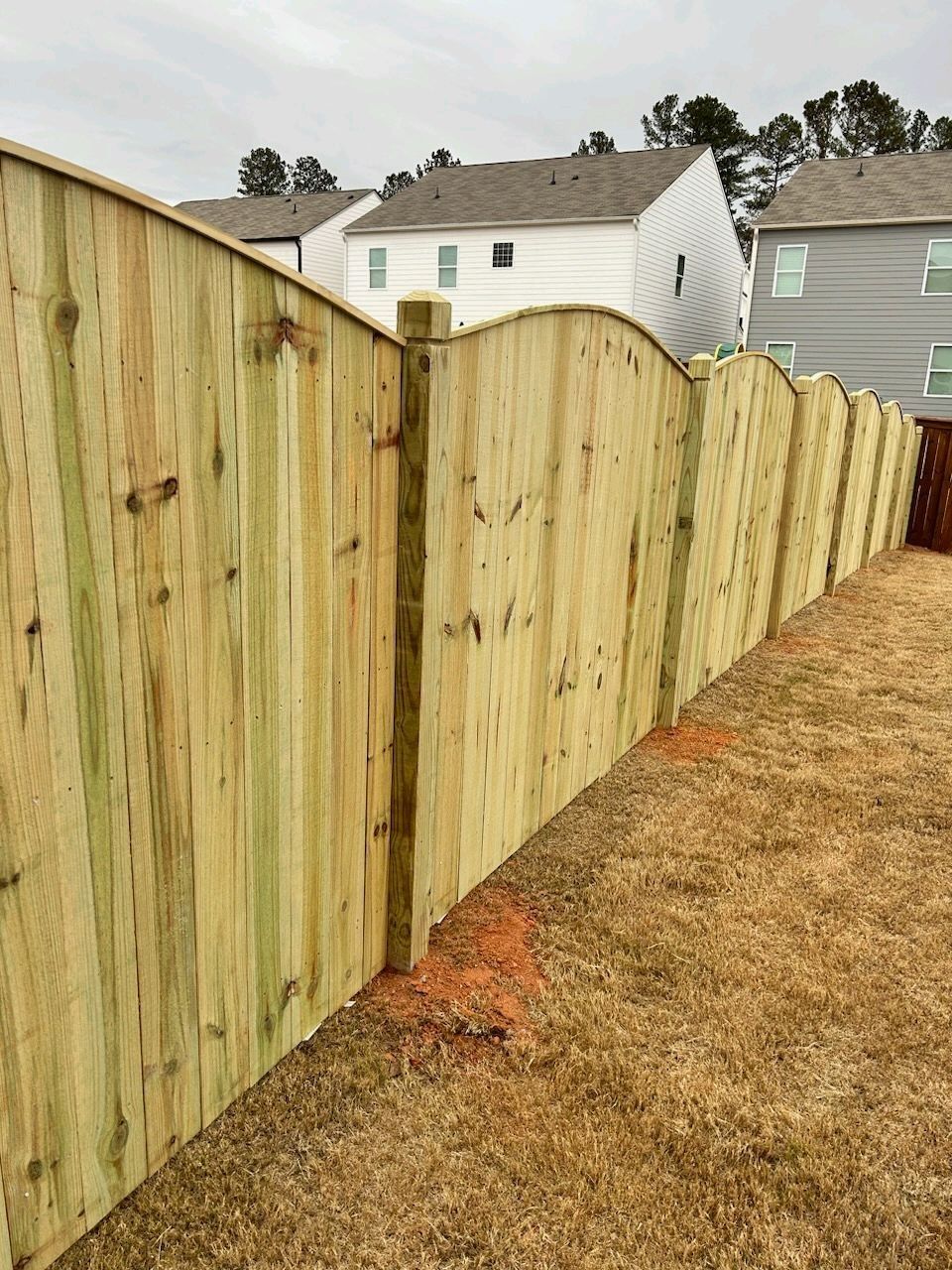 A wooden fence is in the backyard of a house.