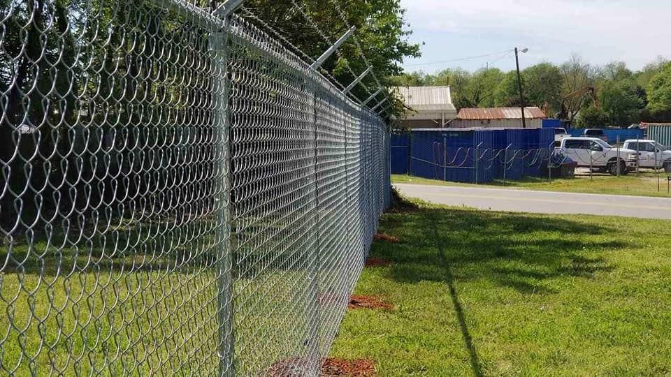 A chain link fence is surrounding a grassy field.
