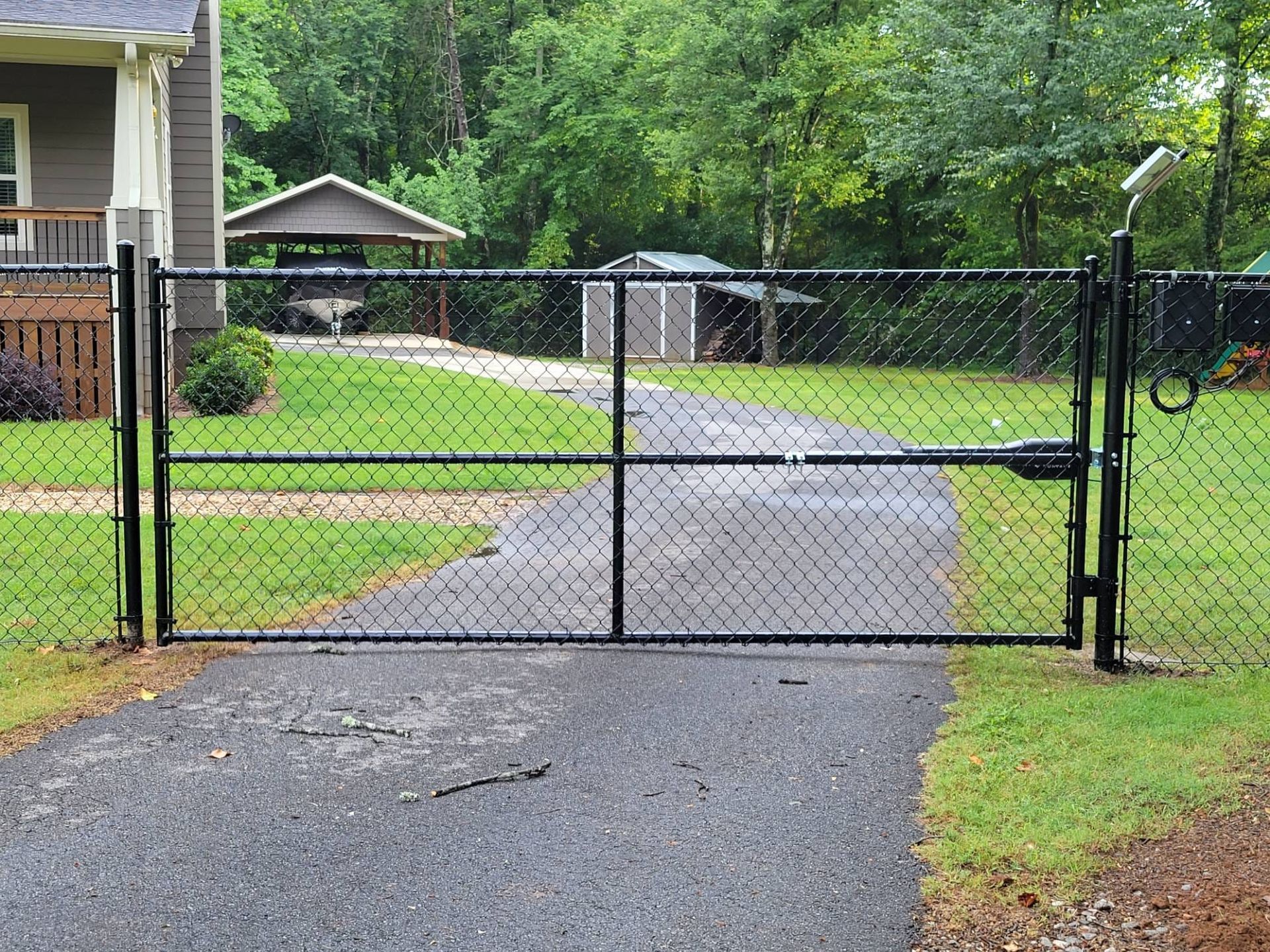 A chain link fence surrounds a driveway leading to a house