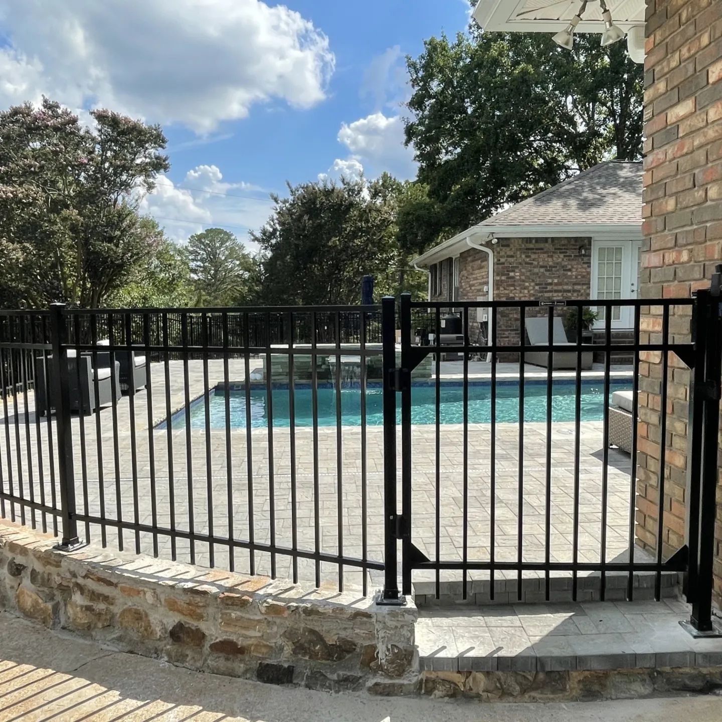 A black metal fence surrounds a swimming pool.