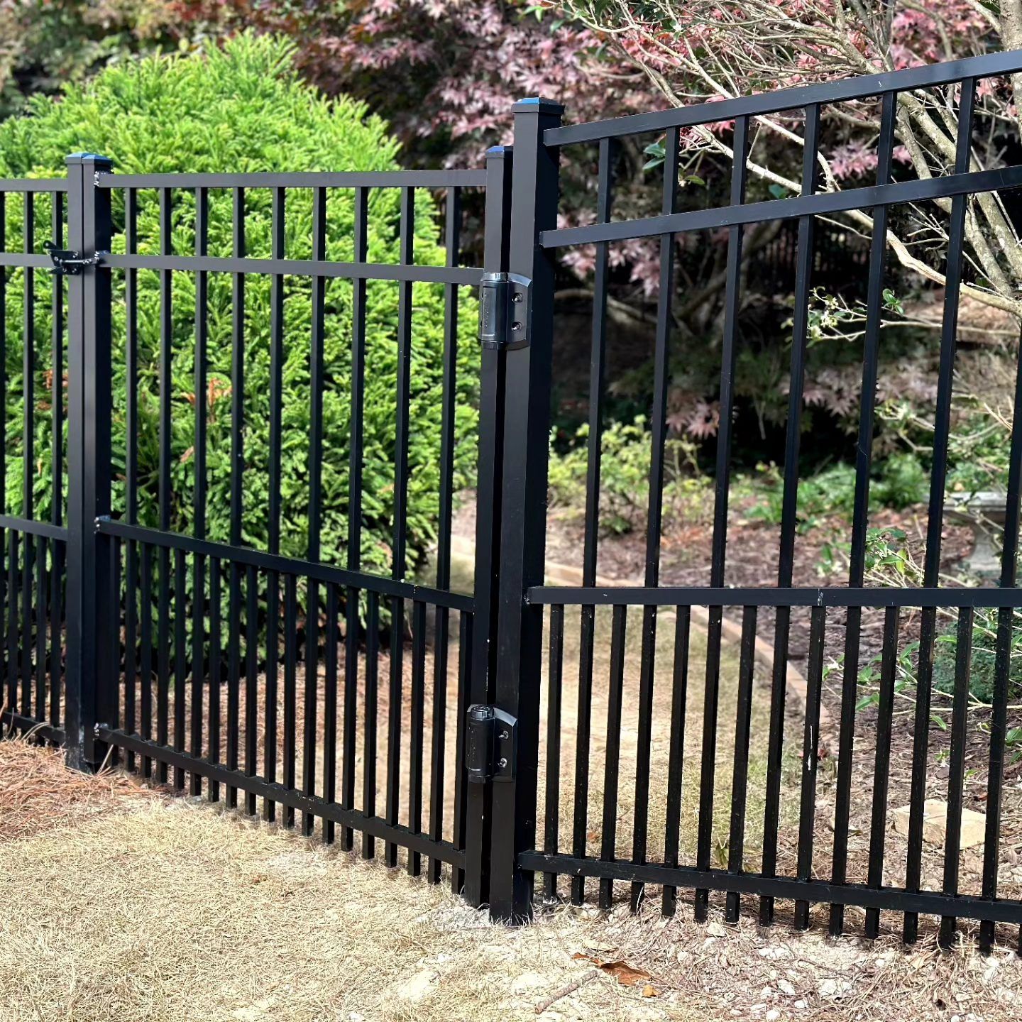 A black metal fence with a gate in the middle of a yard.