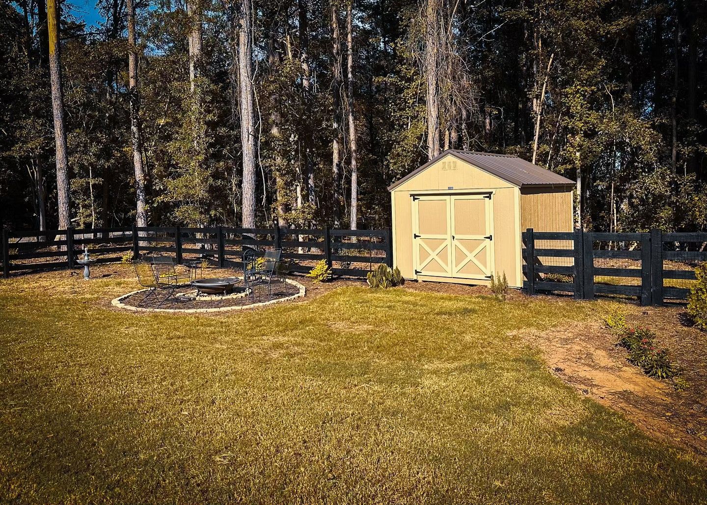 A shed is sitting in the middle of a lush green field surrounded by trees.