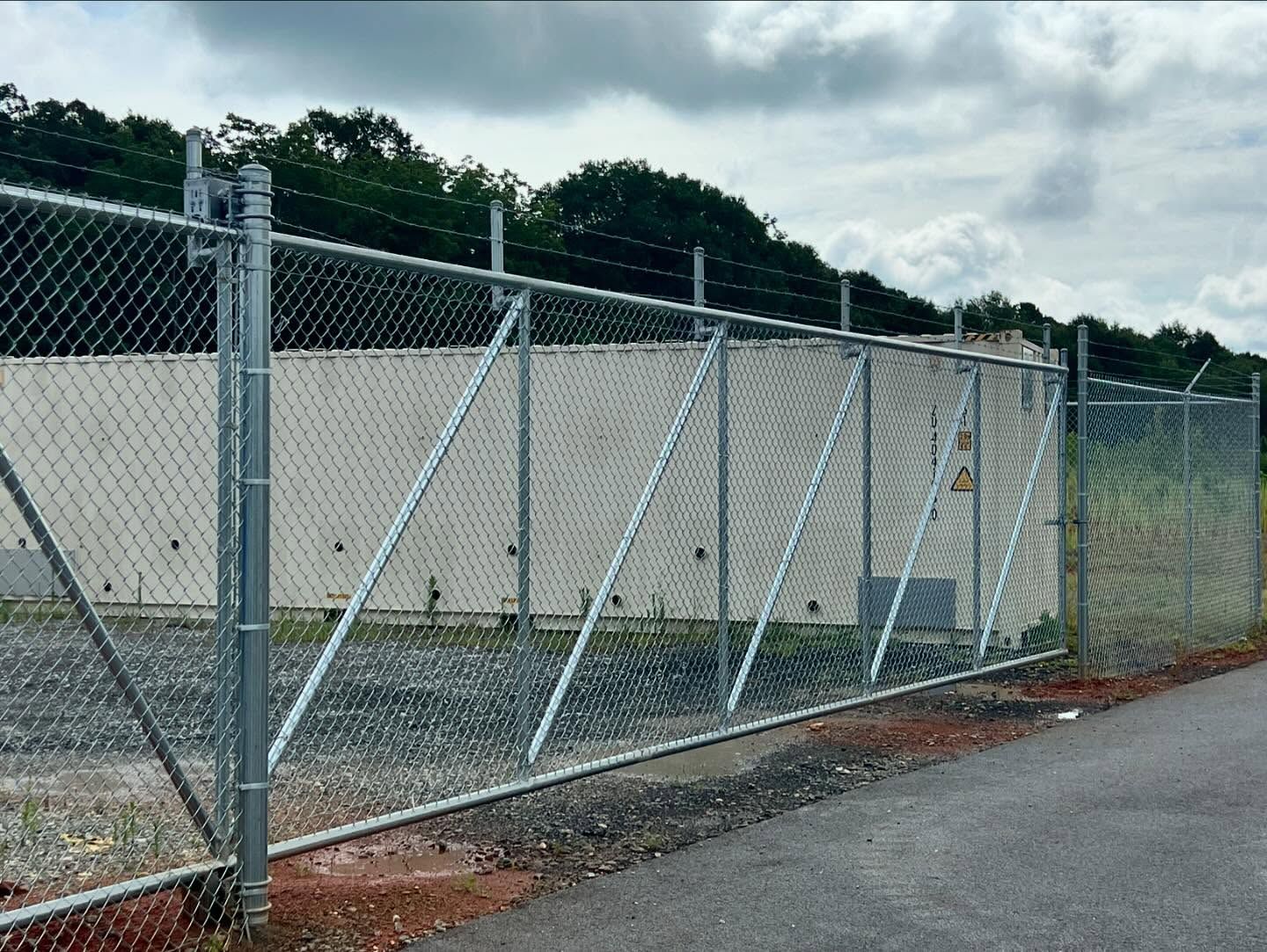 A chain link fence with a sliding gate in front of a building.