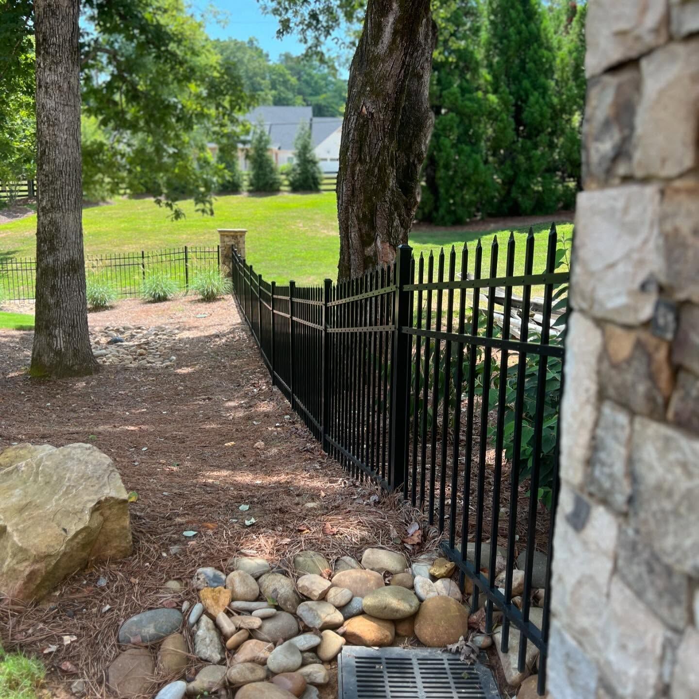 A black fence is surrounded by rocks and trees