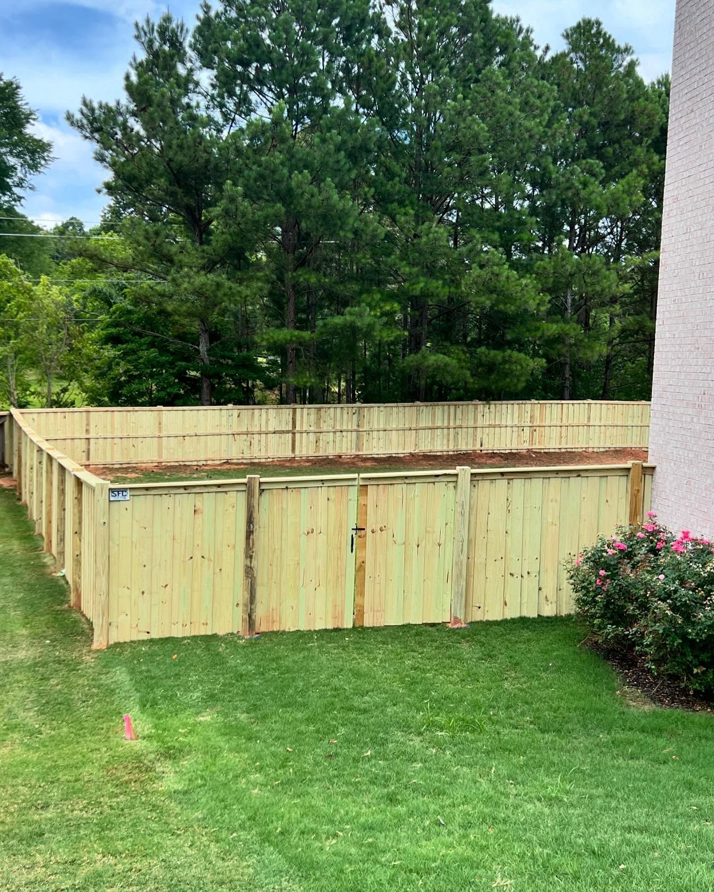 A wooden fence is sitting in the middle of a lush green yard.