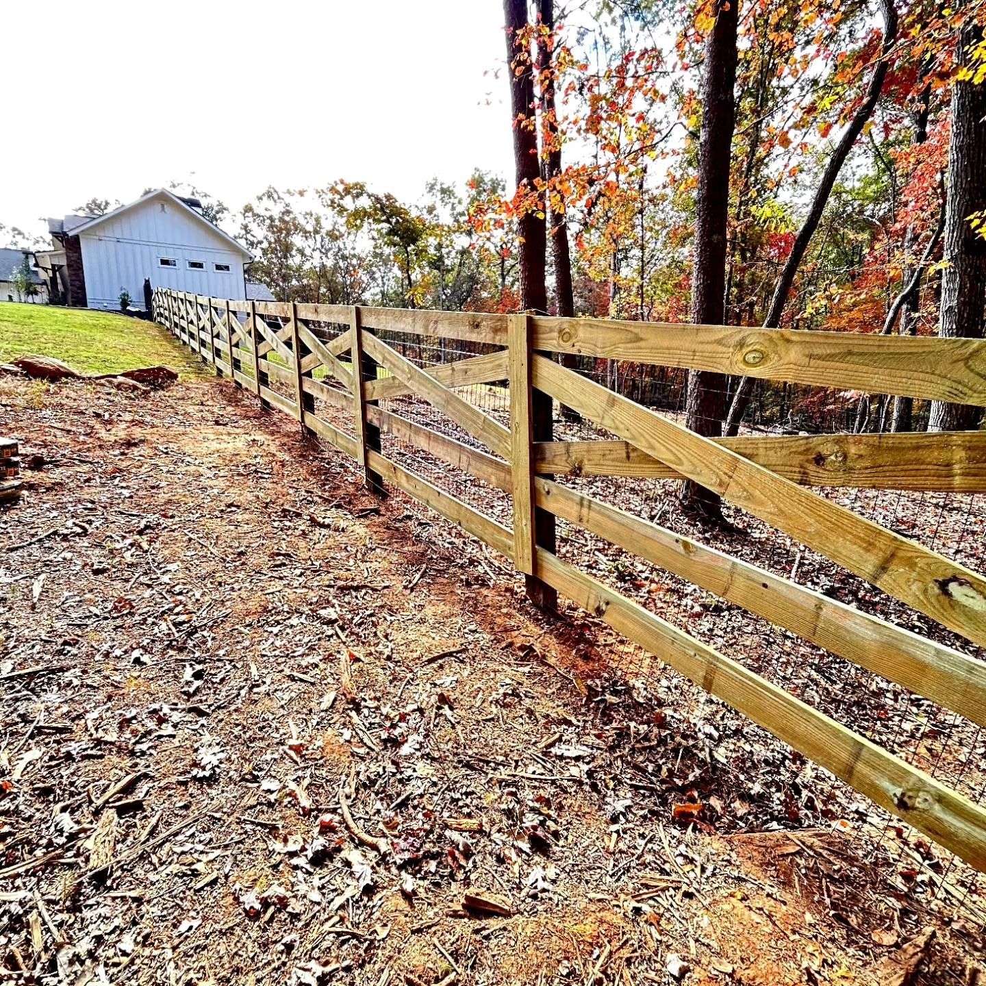 A wooden fence surrounds a yard with a garage in the background.