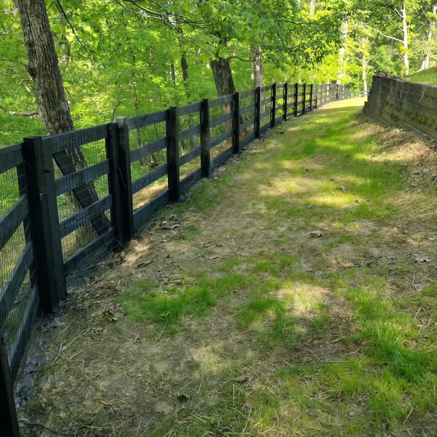 A wooden picket fence is surrounded by dry grass in front of a house.