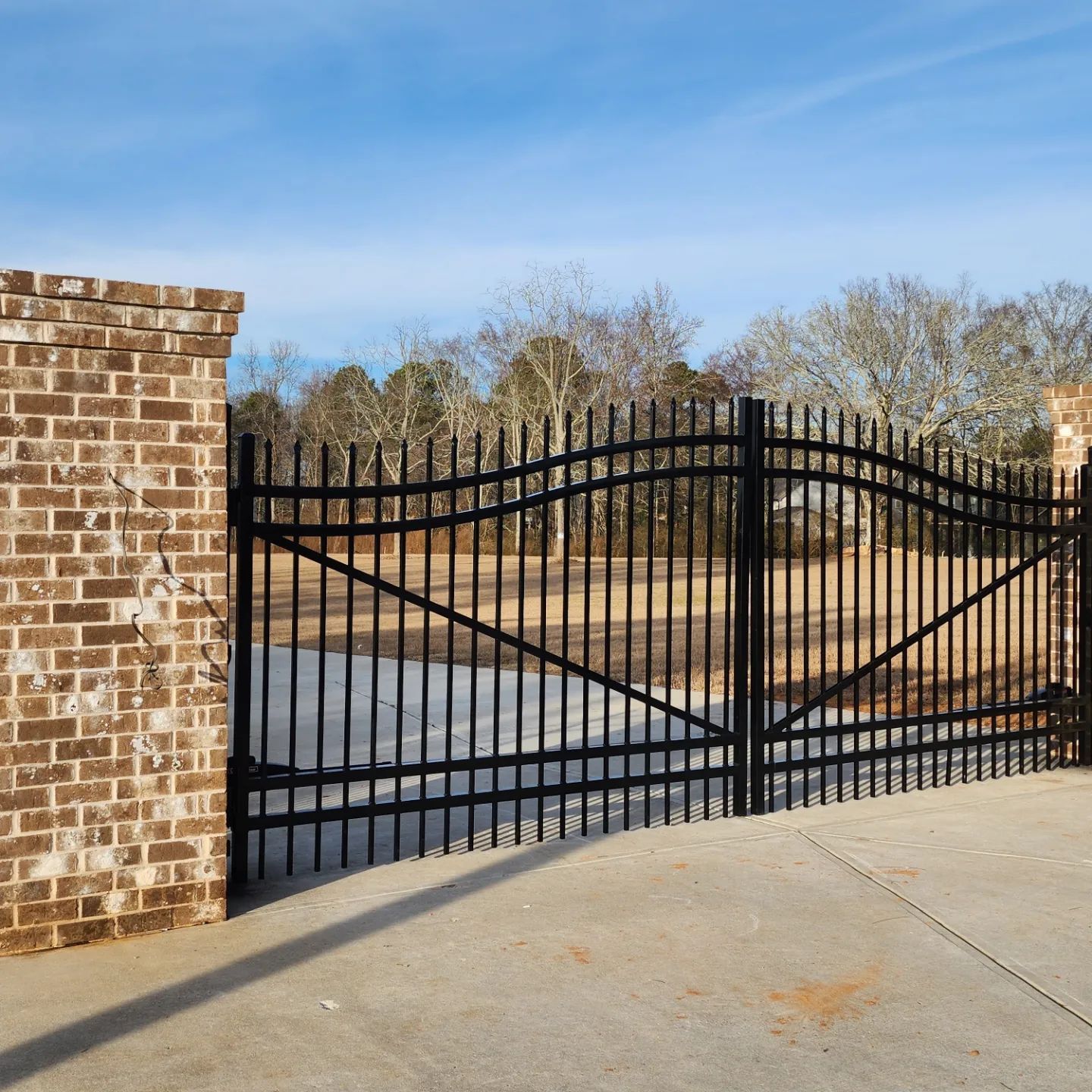 A black gate with a brick wall behind it
