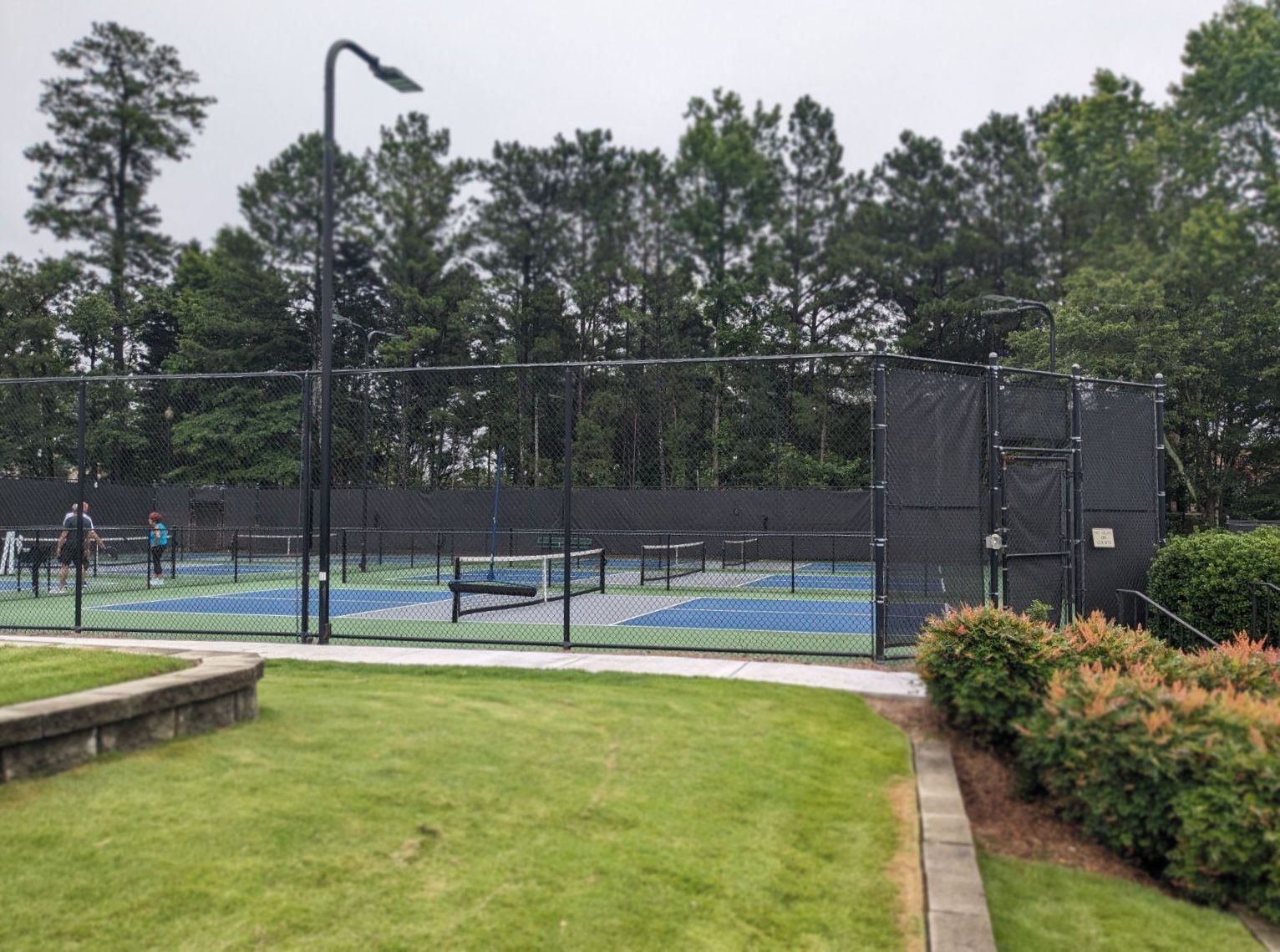 A tennis court with a fence and trees in the background
