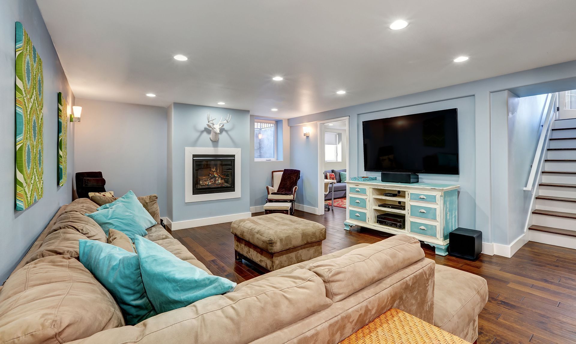 A living room with a couch , ottoman , television and fireplace.