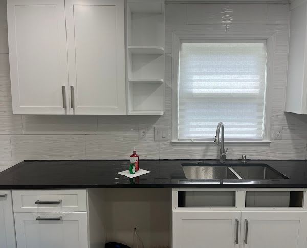 A kitchen with white cabinets, a sink, and a window