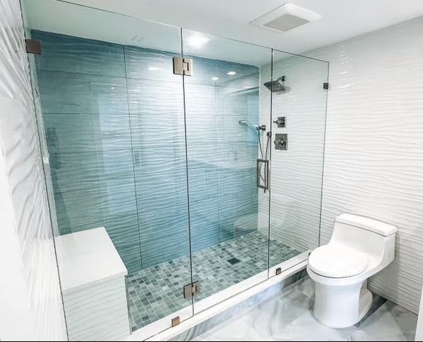 A bathroom with a toilet, shower and glass door
