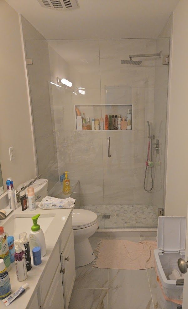 A bathroom with a toilet, sink, shower and mirror