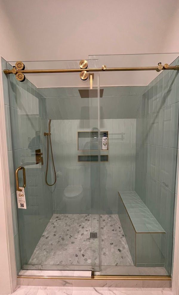 A shower with a sliding glass door and a bench