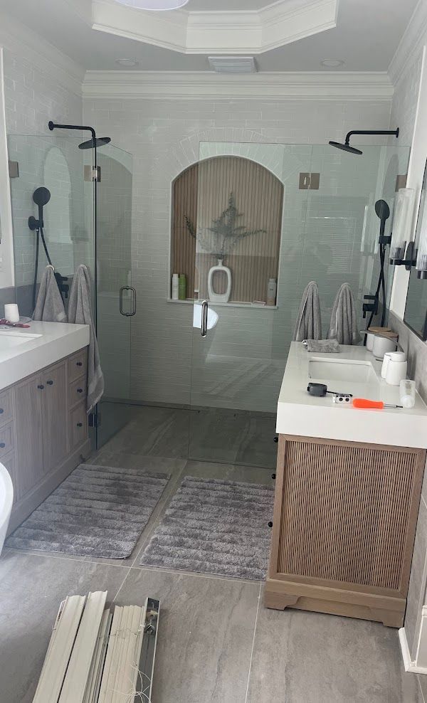A bathroom with two sinks and a walk in shower