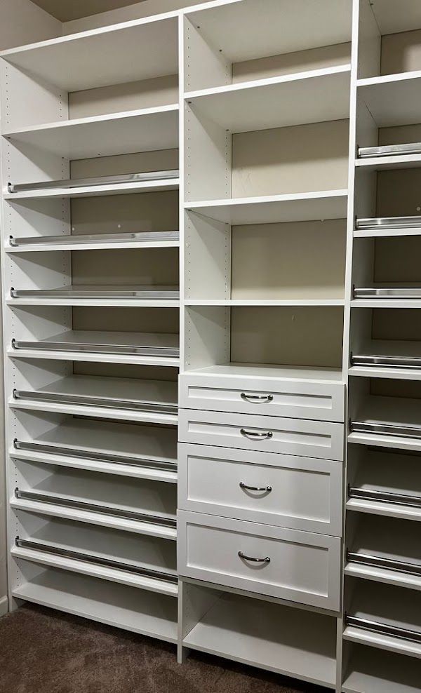 A walk in closet with lots of shelves and drawers