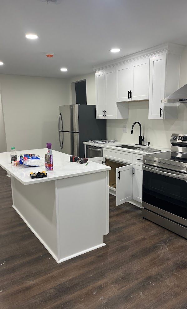 A kitchen with white cabinets, stainless steel appliances, and a large island