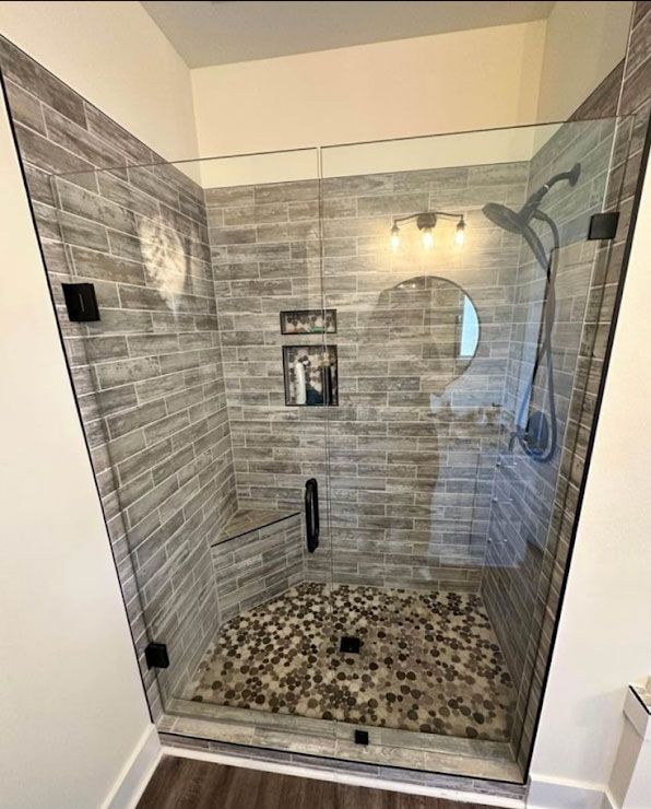 A bathroom with a walk in shower with a glass door