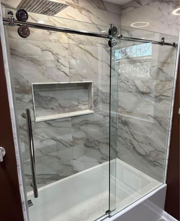 A bathroom with a sliding glass shower door and a bathtub