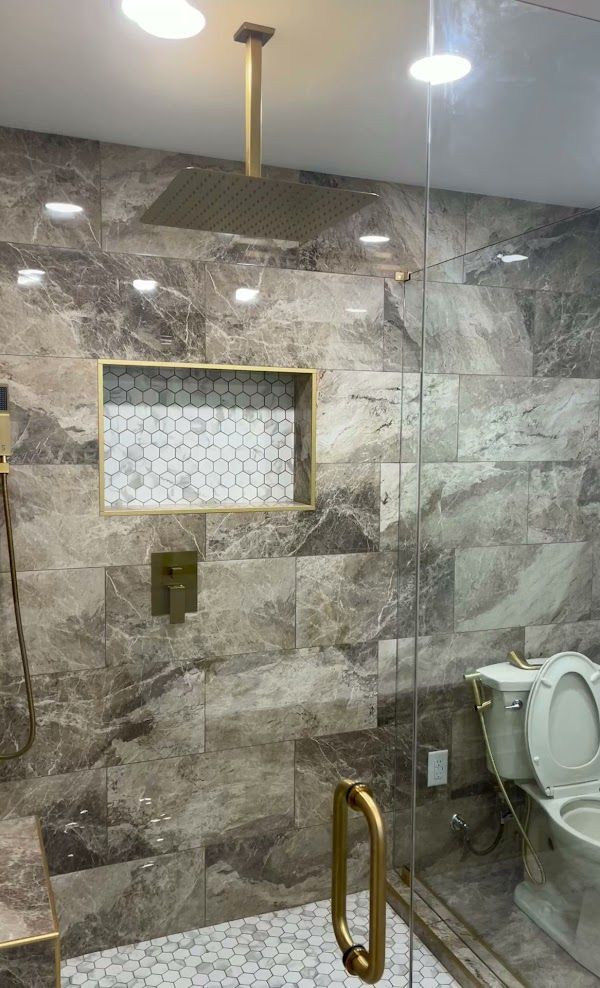 A bathroom with a toilet and a shower with a ceiling mounted shower head
