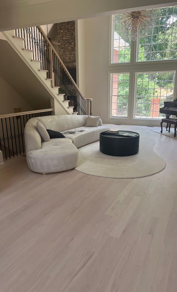 A living room with a couch, ottoman, and piano