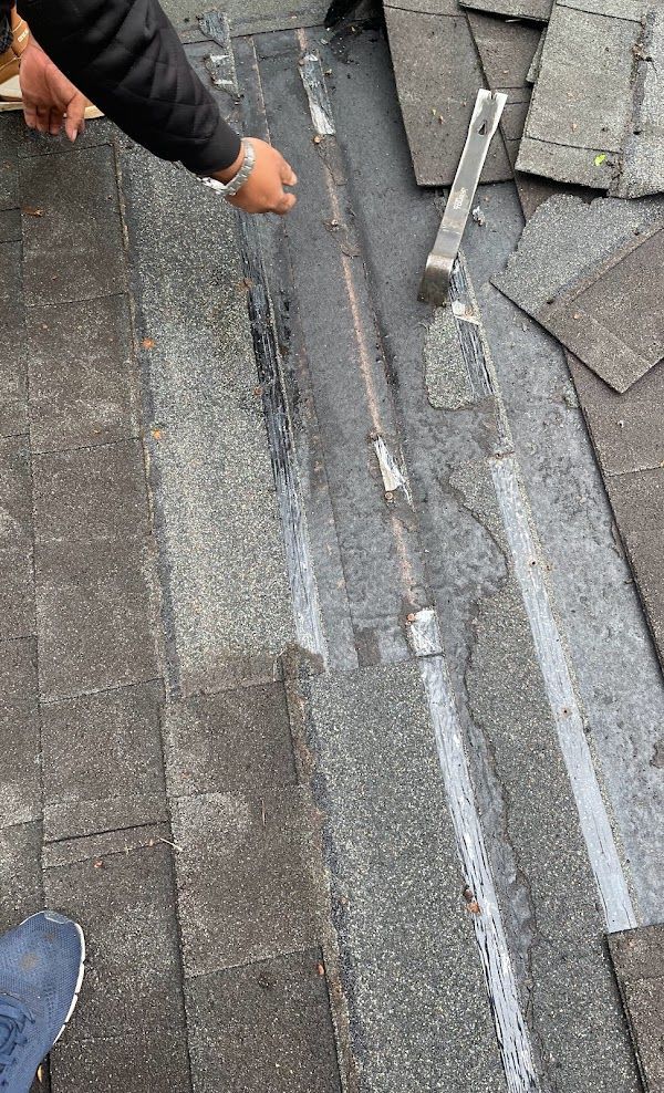 A person is using a brush to clean a drain on a roof