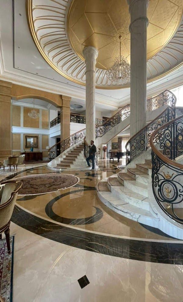 A man is standing in the middle of a large lobby with stairs