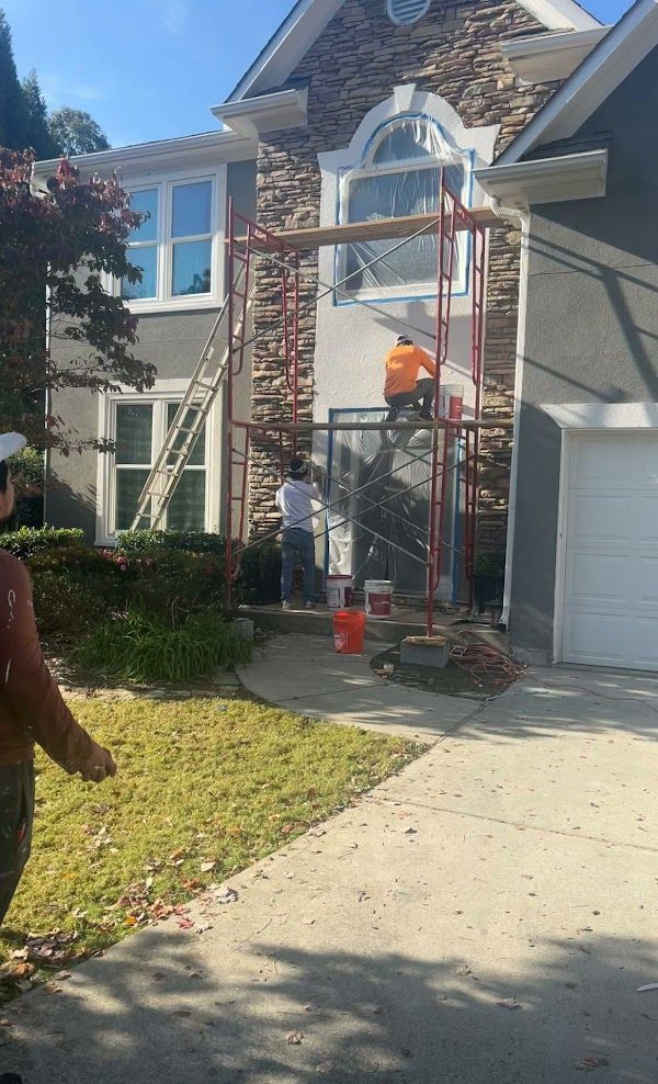 A man is standing in front of a house being painted