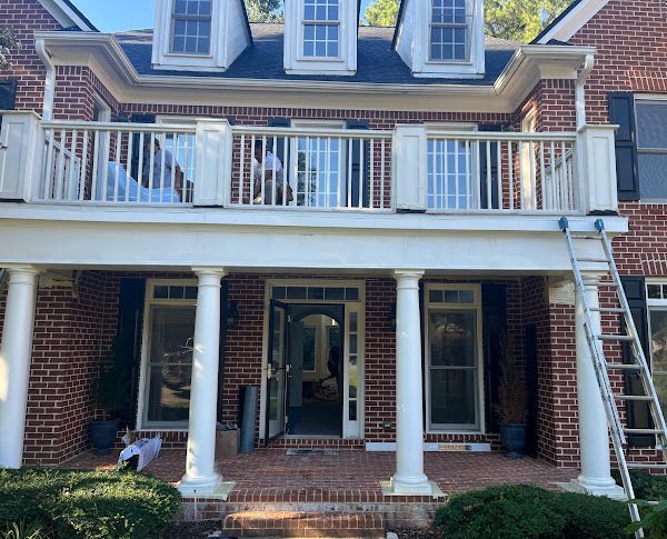 A brick house with a balcony and a ladder on the porch