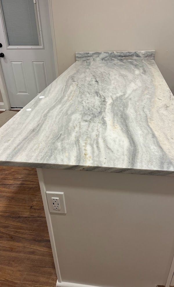 A white marble counter top in a kitchen with a wooden floor