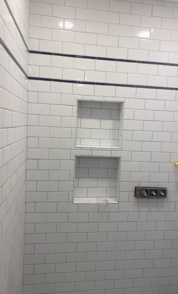 A bathroom with white subway tiles and a shower stall with shelves
