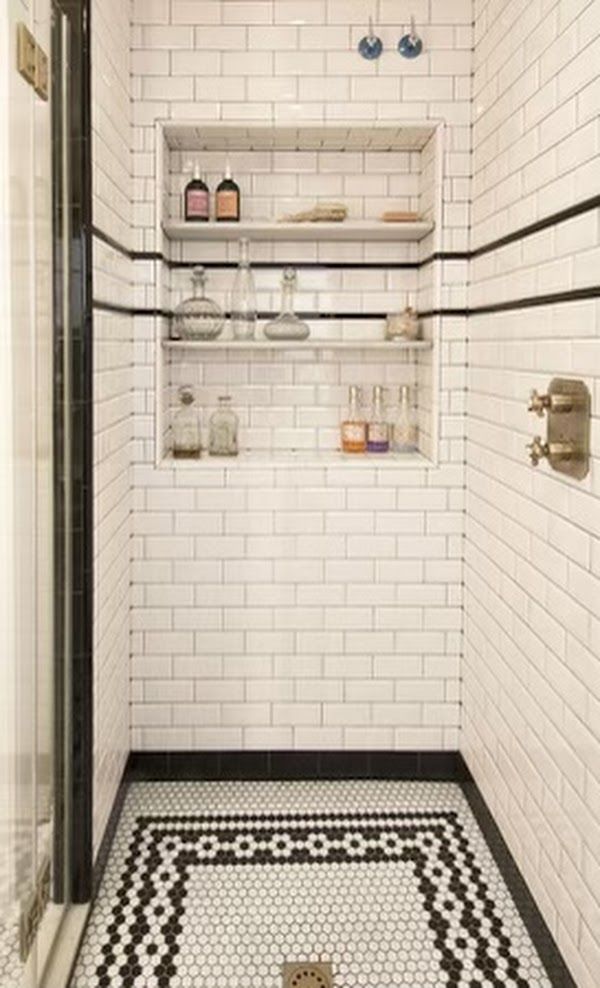 A bathroom with white tiles and a black and white mosaic floor