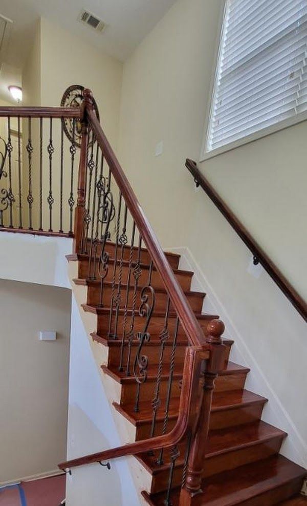 A wooden staircase with a wrought iron railing in a house