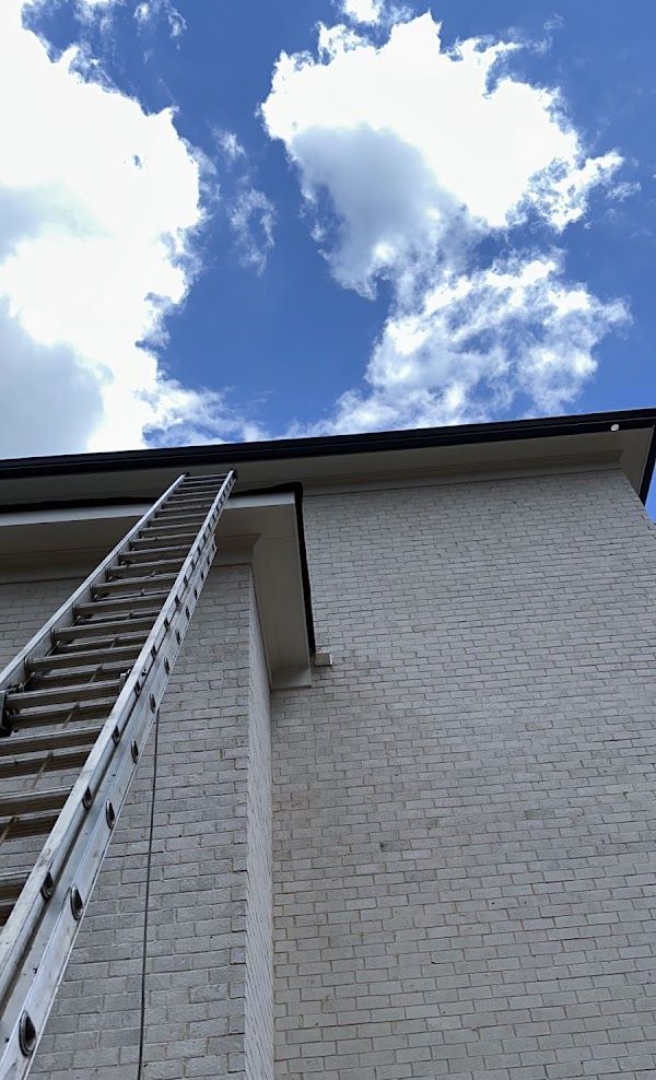A ladder is attached to the side of a white brick building
