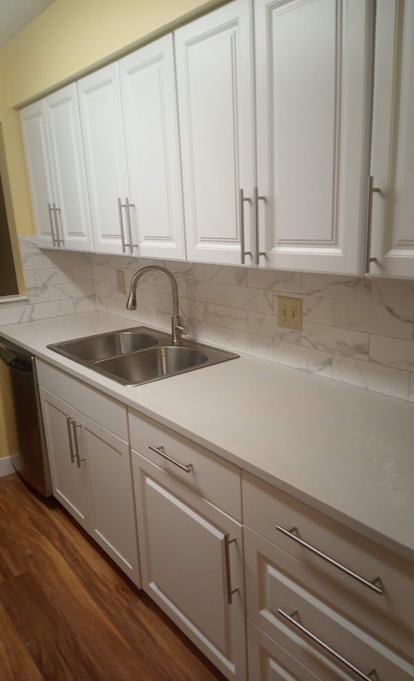 A kitchen with white cabinets and a stainless steel sink
