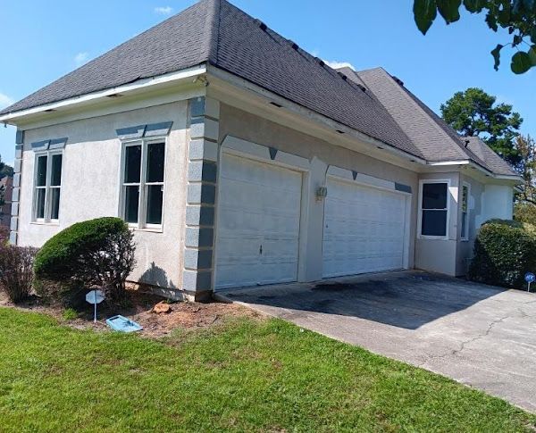 A white house with two garage doors and a gray roof
